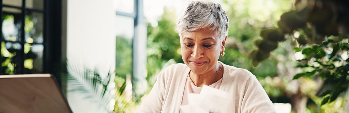 Mature, female person and smile with payslip, invoices or bills at home