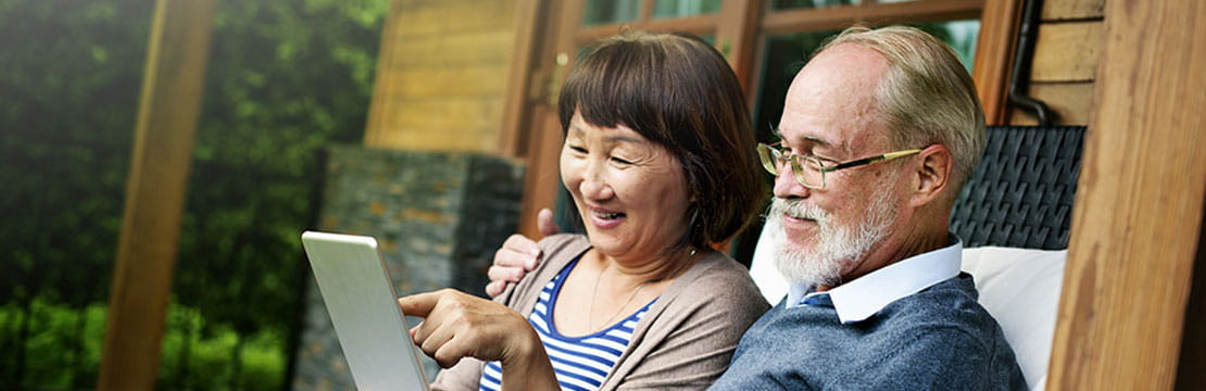 An elderly couple watching something on a tablet